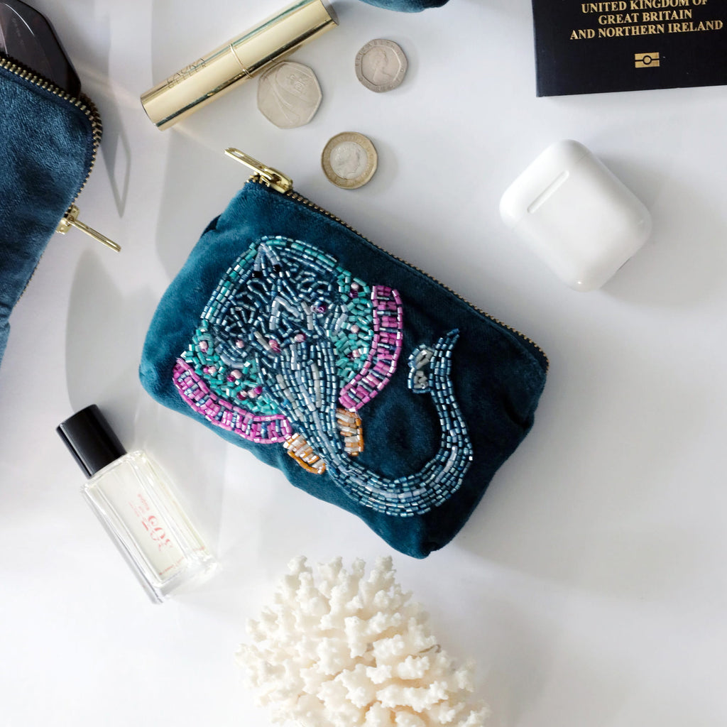 Decorative beaded skate pouch with travel items on a white surface