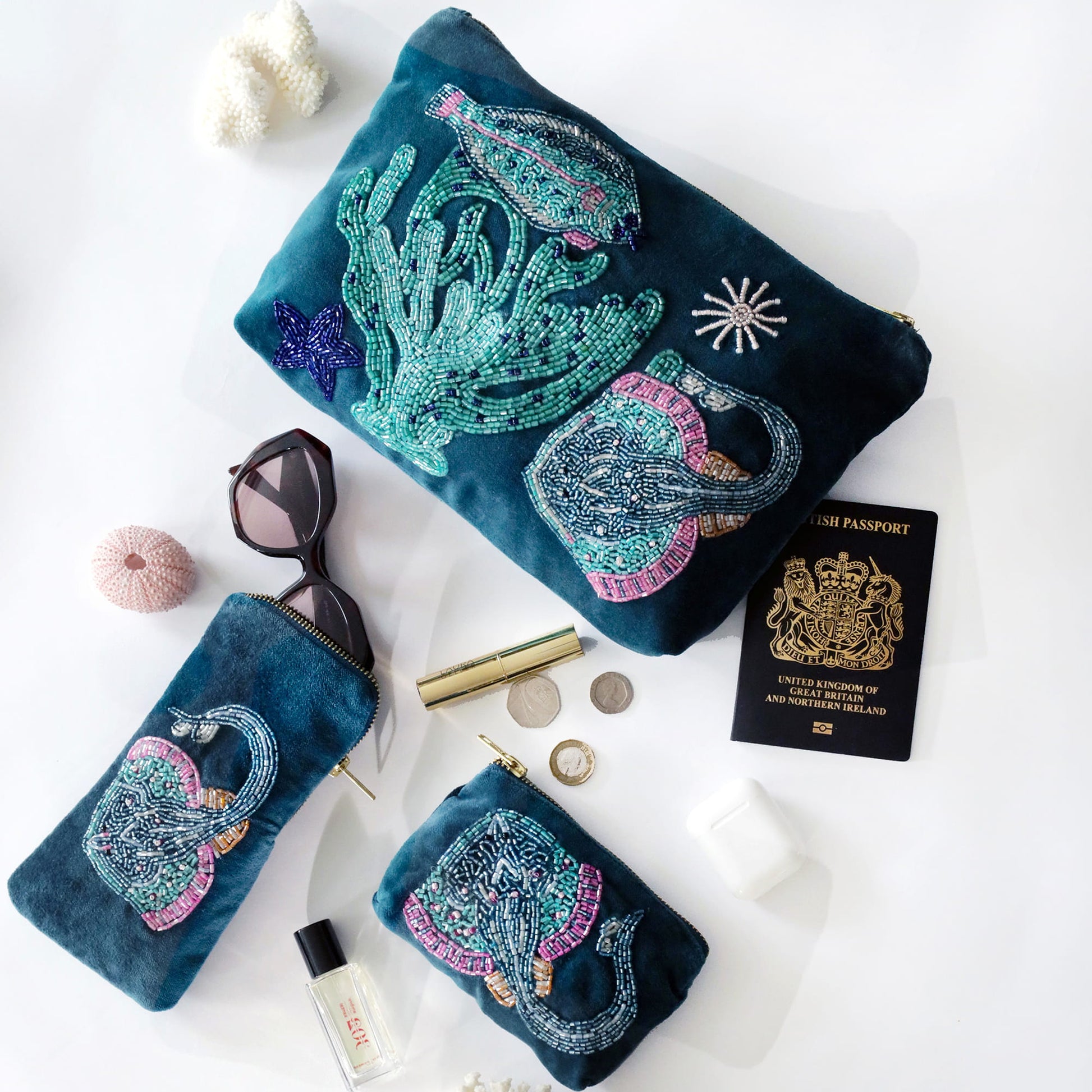Set of blue pouches with ocean-themed designs on a white surface with accessories.