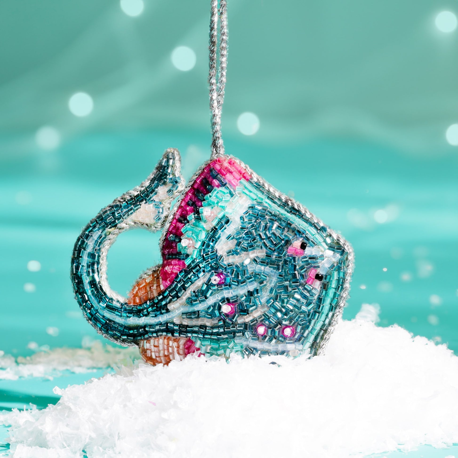 Decorative Christmas ornament shaped like a skate fish with coluorful beads against a snowy background