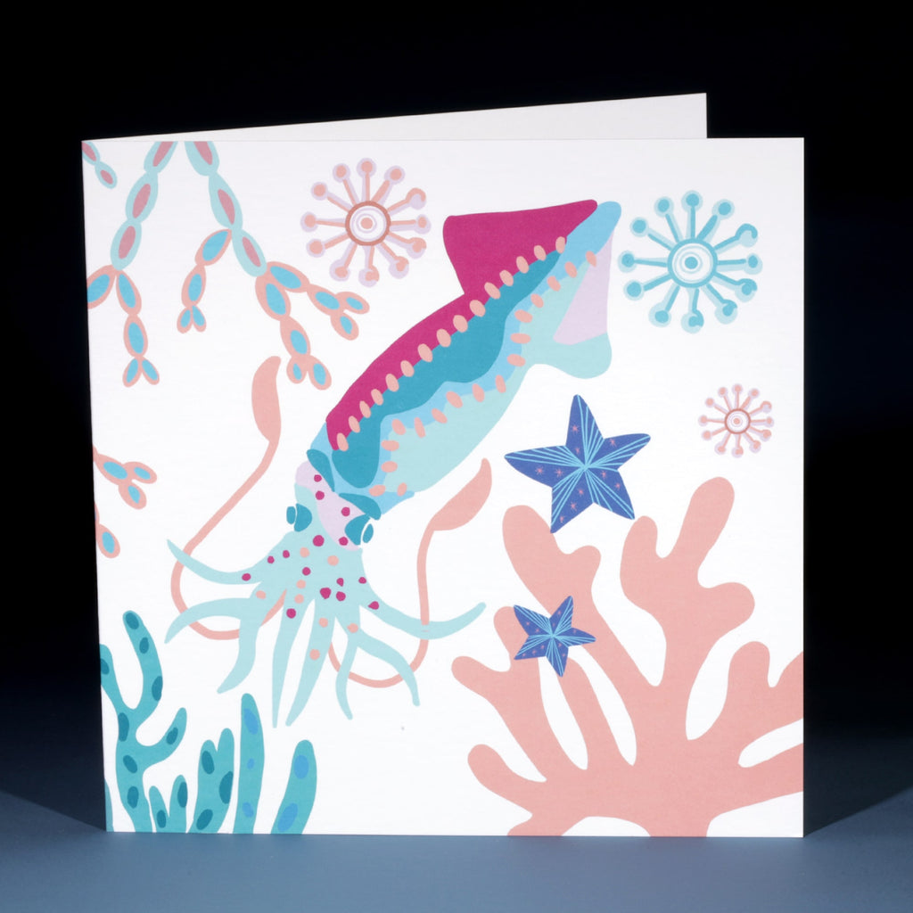 An illustrated greeting card featuring a vibrant and playful squid surrounded by coral, seaweed, and starfish in shades of blue, pink, and turquoise. The design is whimsical and ocean-inspired, with circular sea motifs floating around the squid.