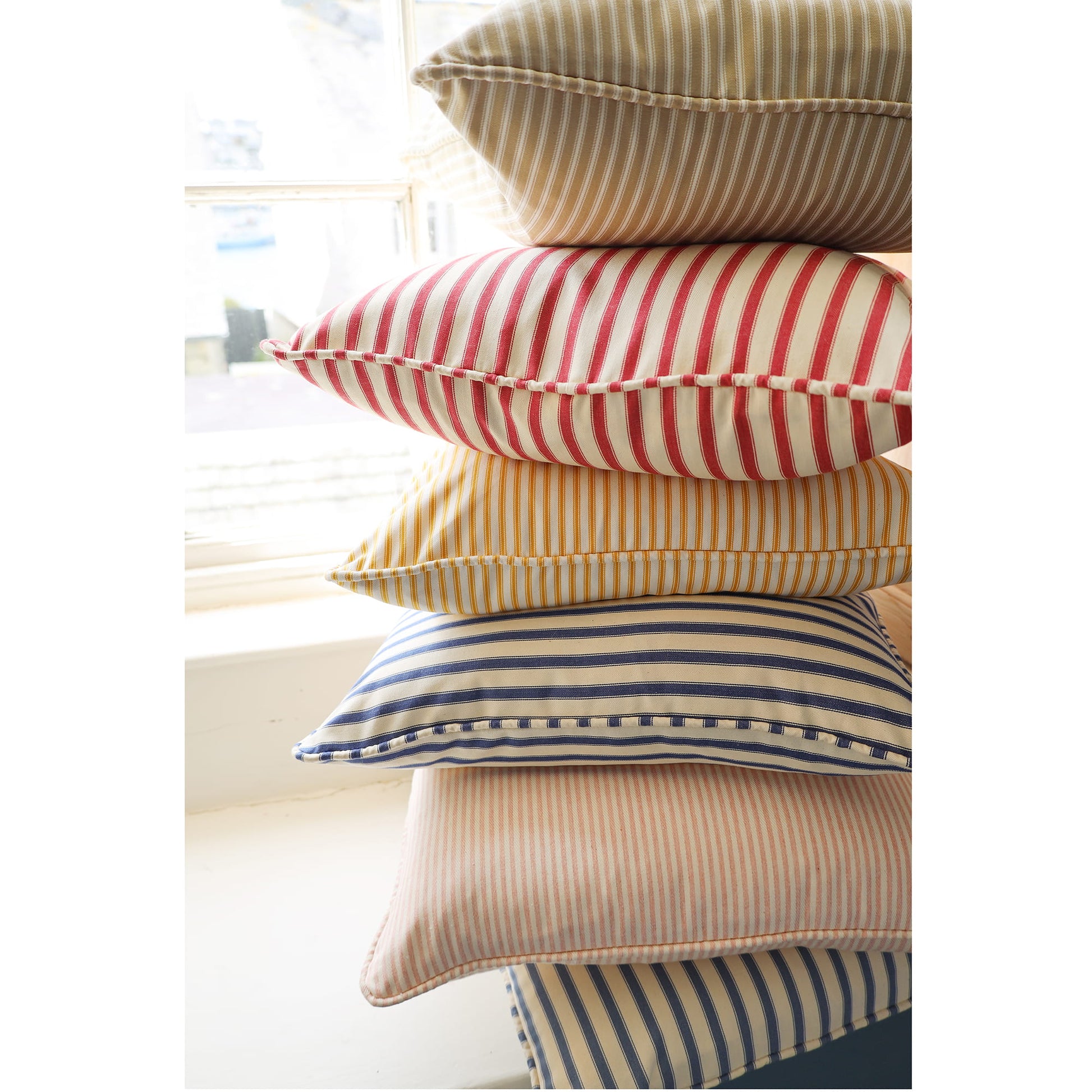 Stack of striped pillows in various colors on a light background