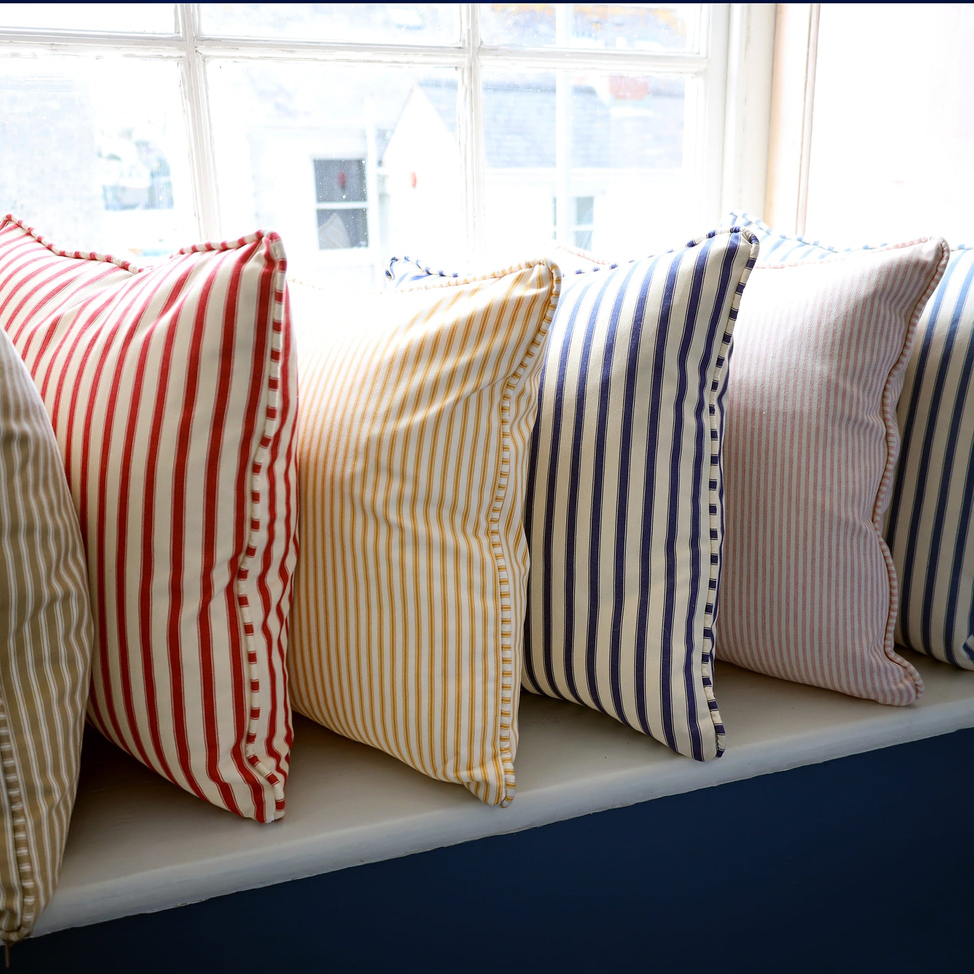 Colorful striped pillows on a window sill with a blurred outdoor background