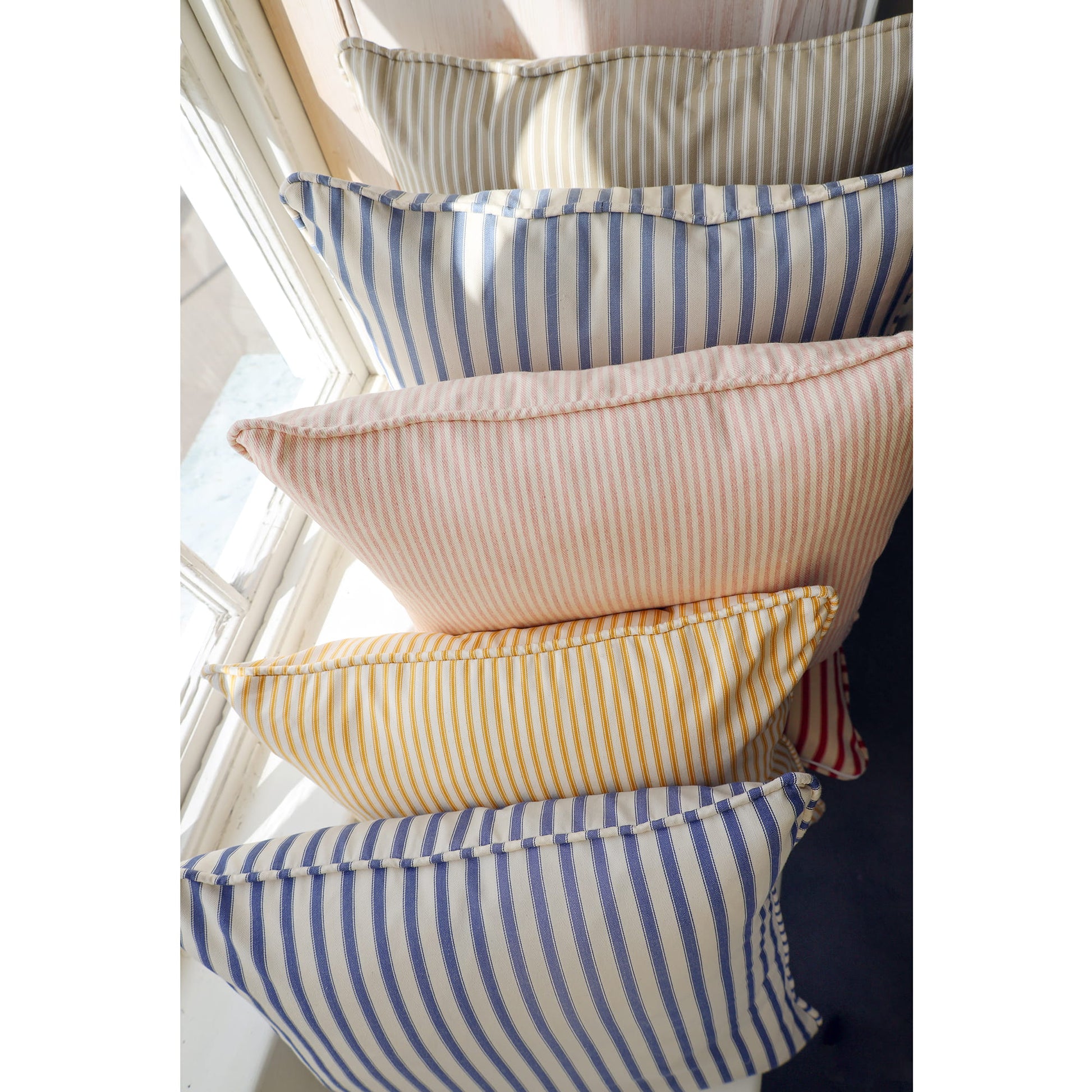 Stack of striped pillows in various colors against a neutral background