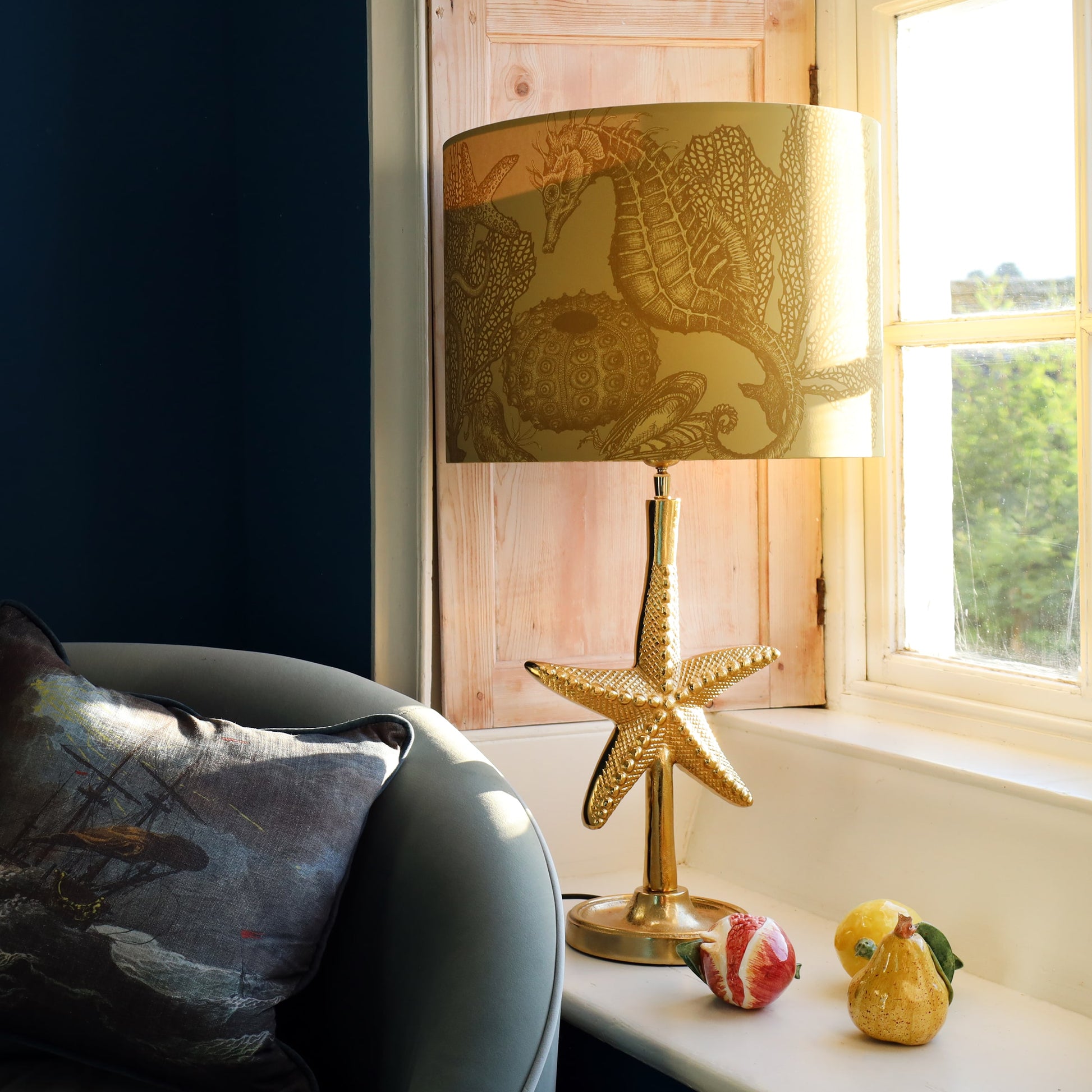 Decorative gold lamp with starfish design on a windowsill next to a sofa.