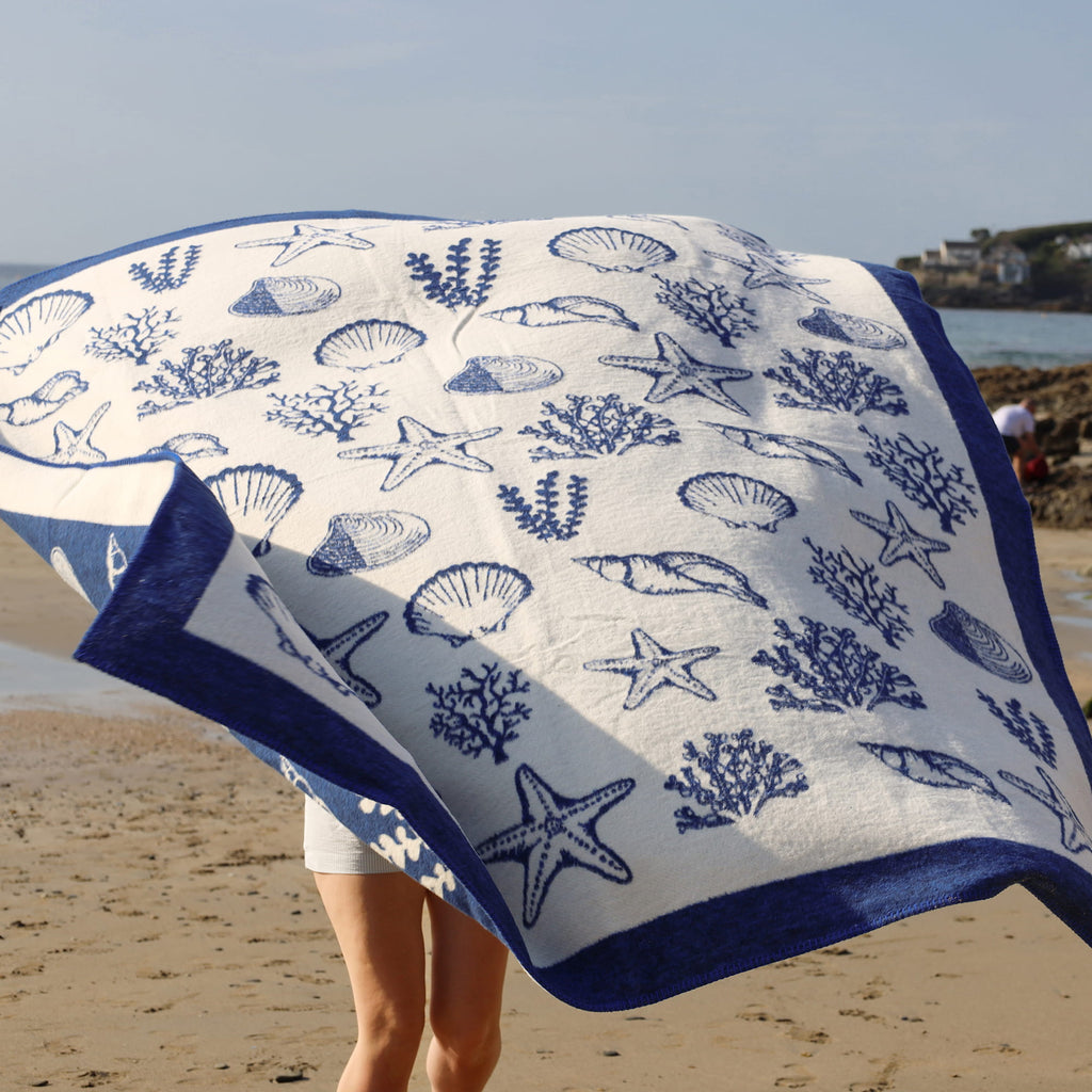 Beach towel with blue sea-themed pattern on a sandy beach