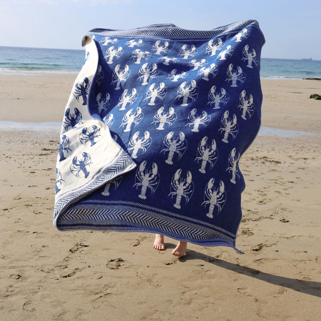 Blue towel with white lobster pattern on a sandy beach