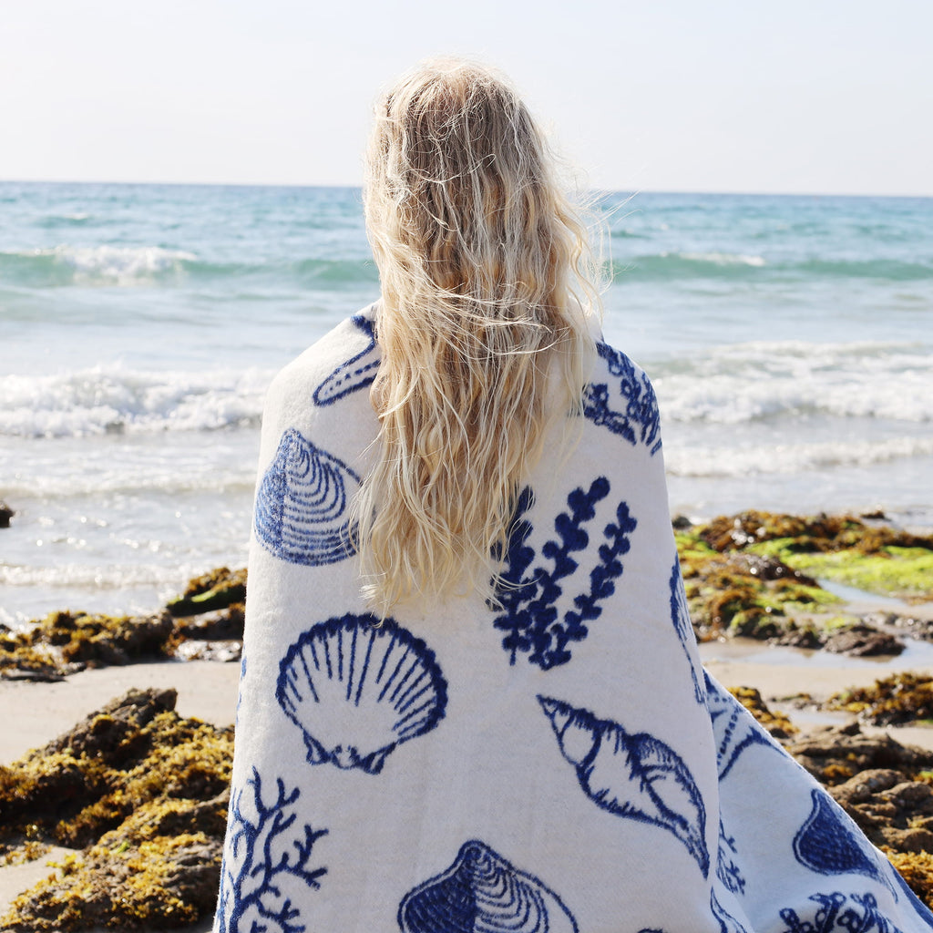 Person wrapped in a blue and white patterned towel on a beach