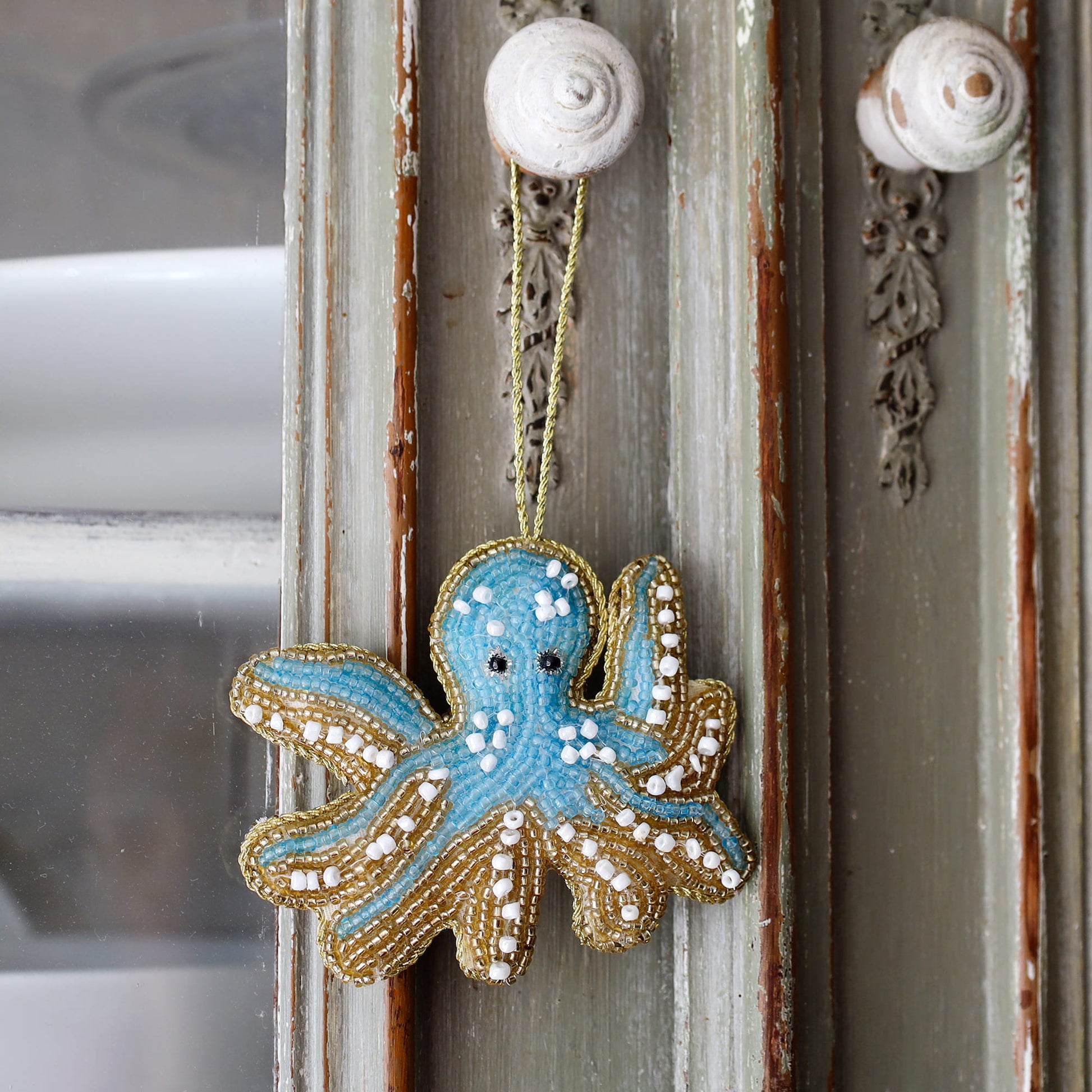 Decorative octopus ornament hanging on a door with shell decorations.