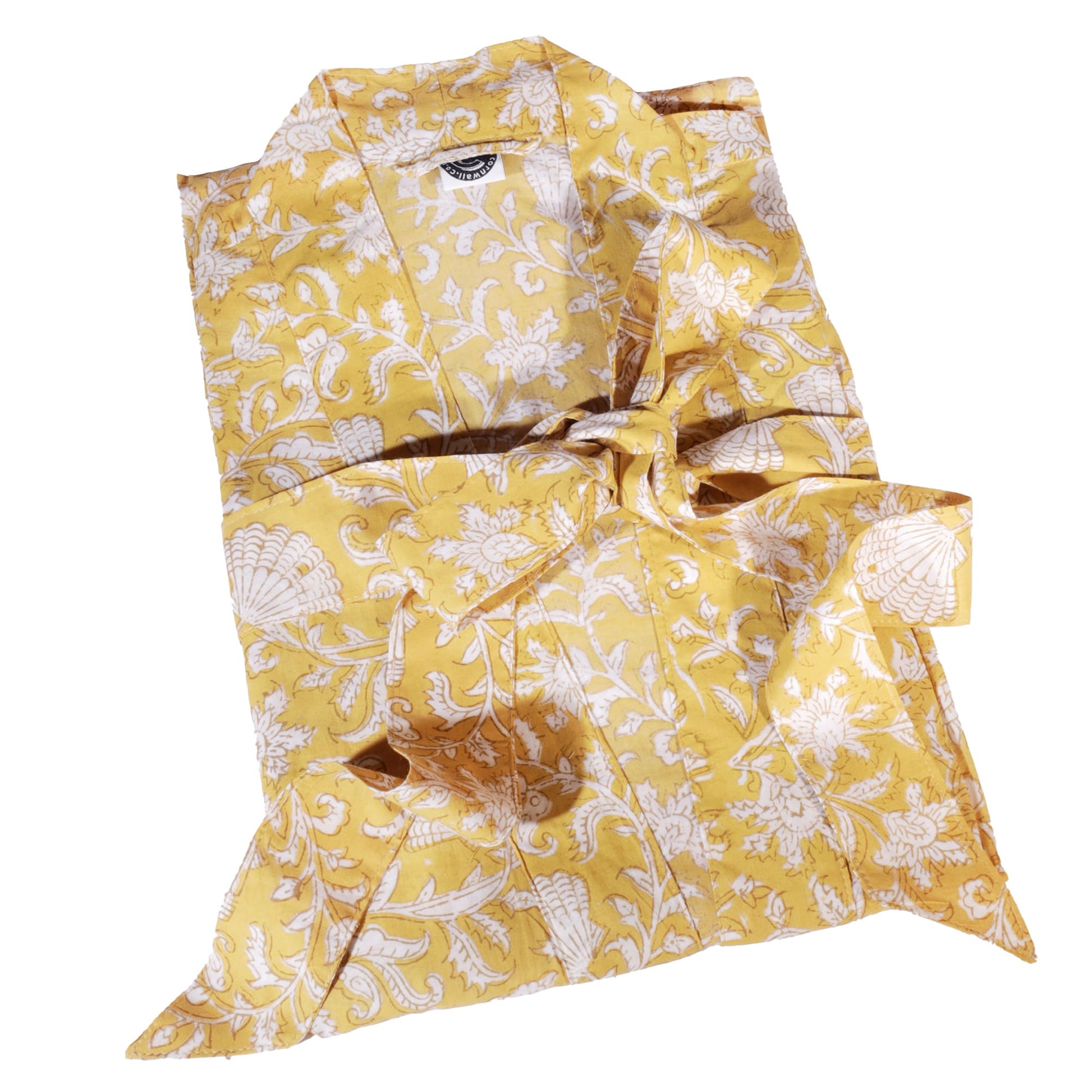 Yellow dressing gown featuring intricate white floral and seashell block print patterns, neatly folded and tied with a matching fabric belt for a stylish presentation.
