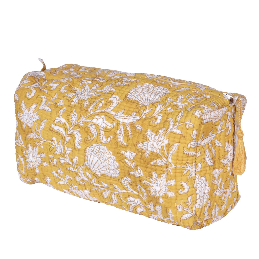 Yellow quilted washbag featuring intricate white floral and seashell block print patterns. The bag includes a tassel detail on the zipper, adding a stylish and functional touch.