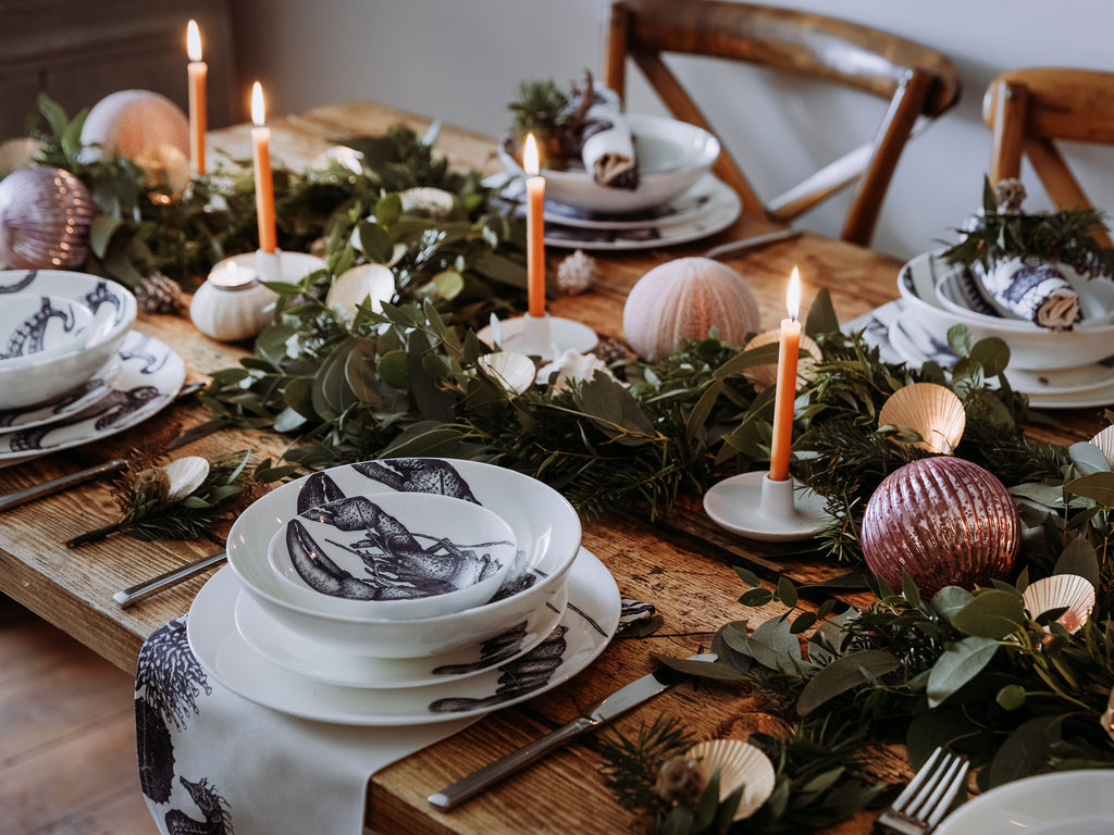 Pasta bowl in Bone China in our Classic range in Navy and white in the Lobster design,placed on a matching dinner plate and has a smaller bowl placed inside.All are on a table setting and the table is decorated with foliage and candle holders