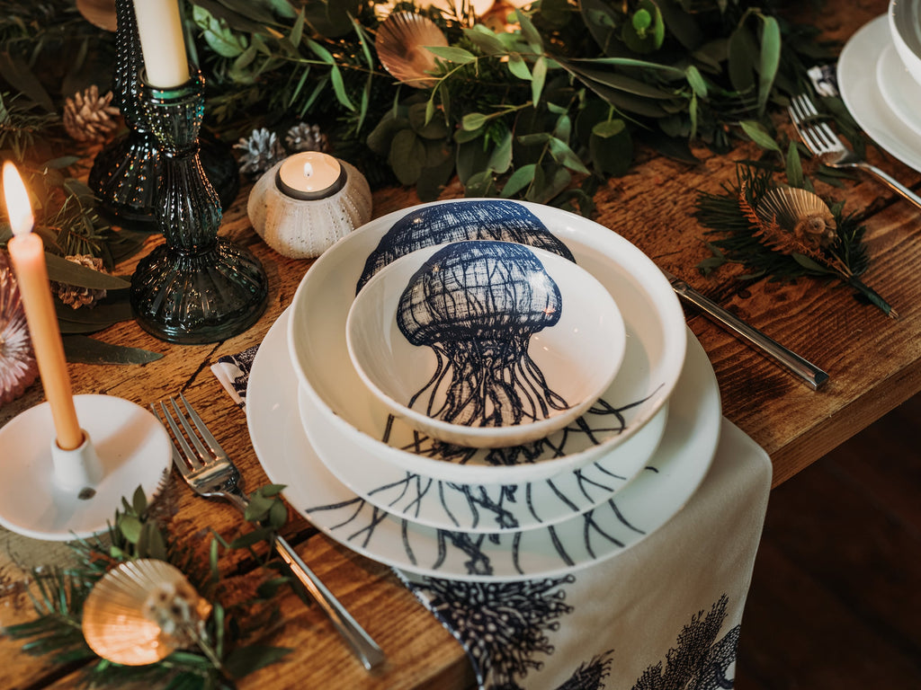 Pasta bowl in Bone China in our Classic range in Navy and white in the Jellyfish design,placed on a matching dinner plate and has a smaller bowl placed inside.All are on a table setting and the table is decorated with foliage and candle holders