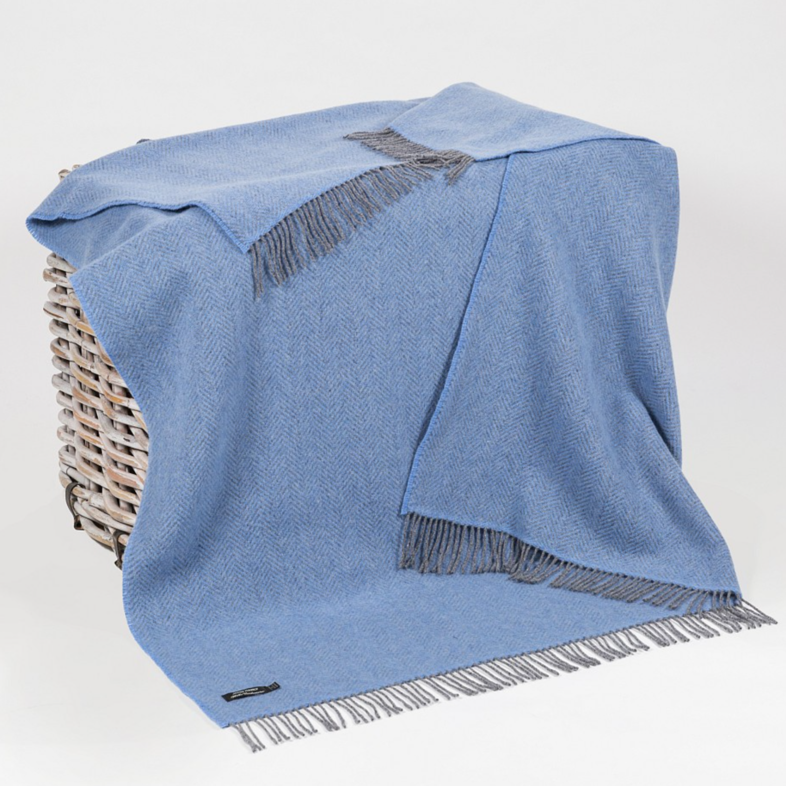 Cashmere Throw Grey Blue Herringbone draped over a basket