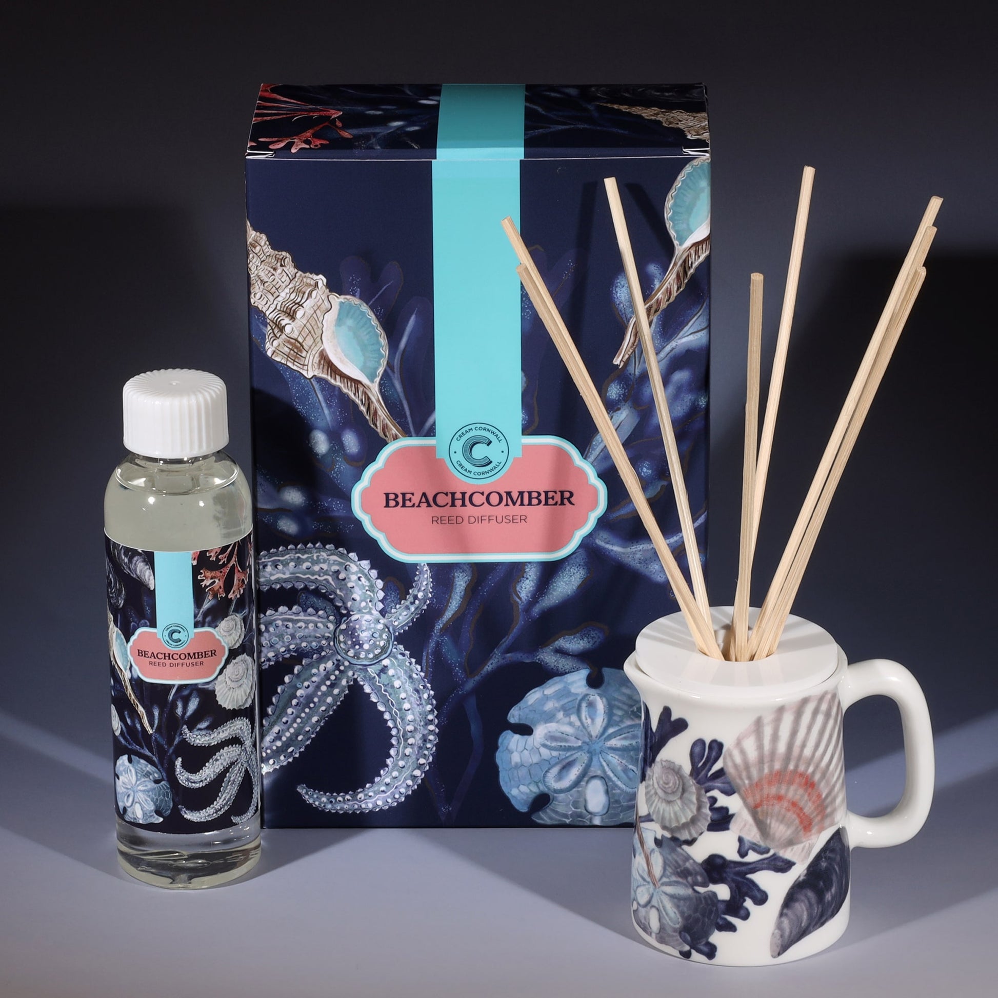 Beachcomber room diffuser with natural reeds in front of the product box and a bottle of diffuser liquid.