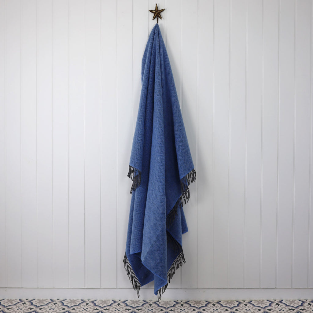 Cashmere Throw Grey Blue Herringbone draped on a Starfish hook against a white tongue and grooved wall