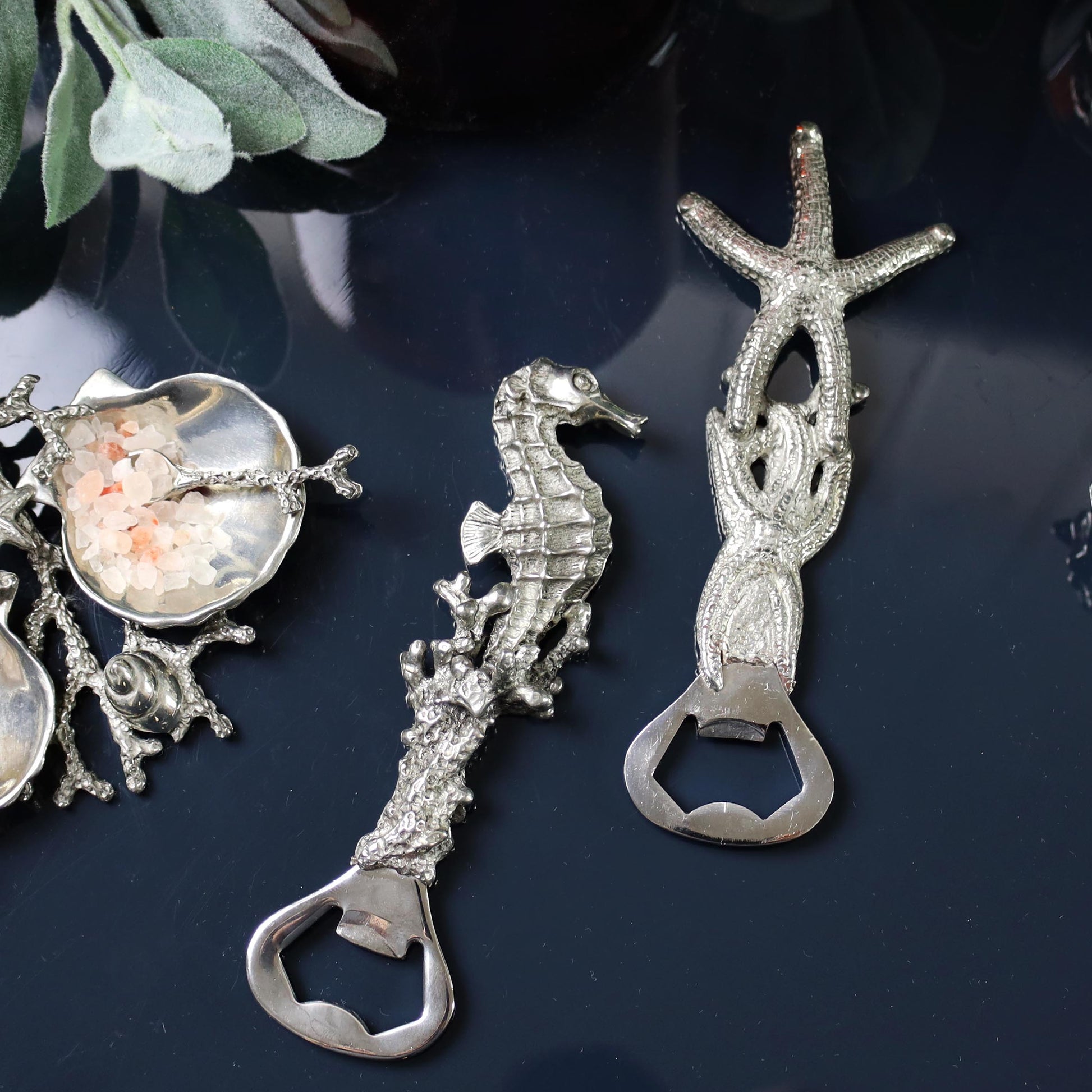 Pewter Seahorse and a Shell shaped Bottle Opener placed on a table