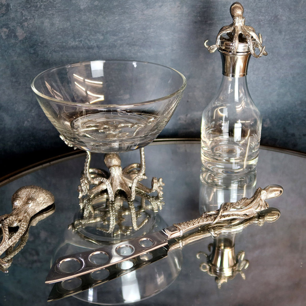 Pewter Octopus  Pie Knife placed on a mirror table,the octopus is wrapped around the handle.On the table are several other Octopus Pewter items
