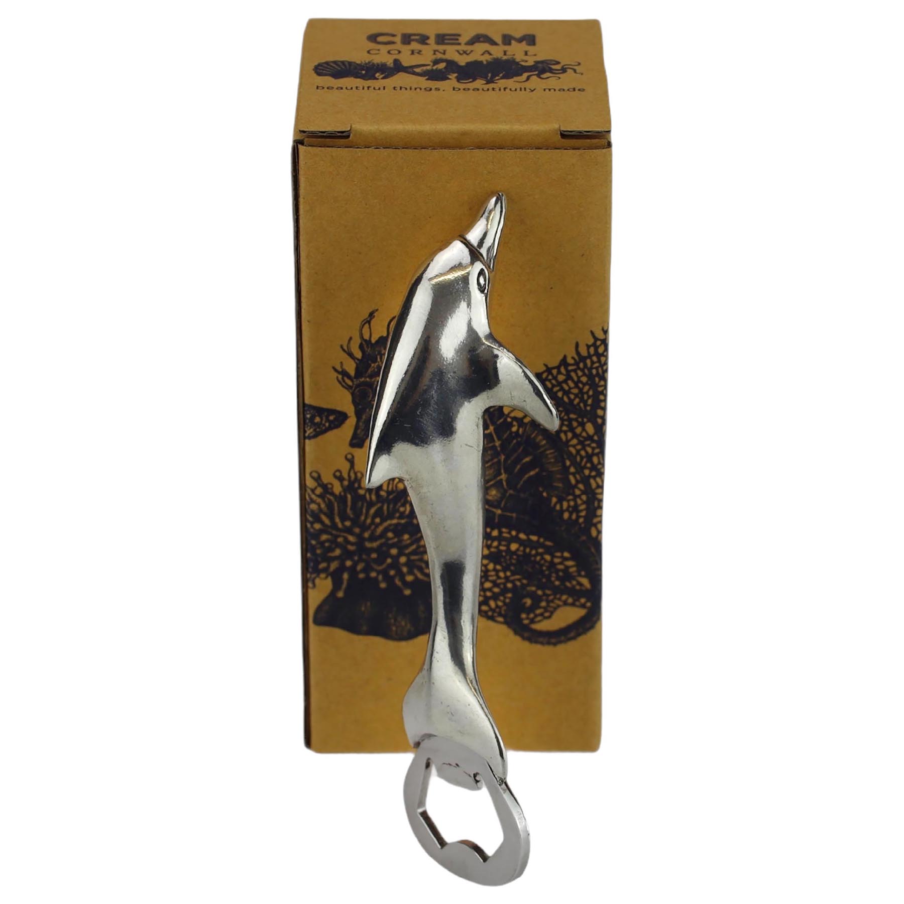 Pewter Dolphin Bottle Opener  on its side in front of a cream cornwall box