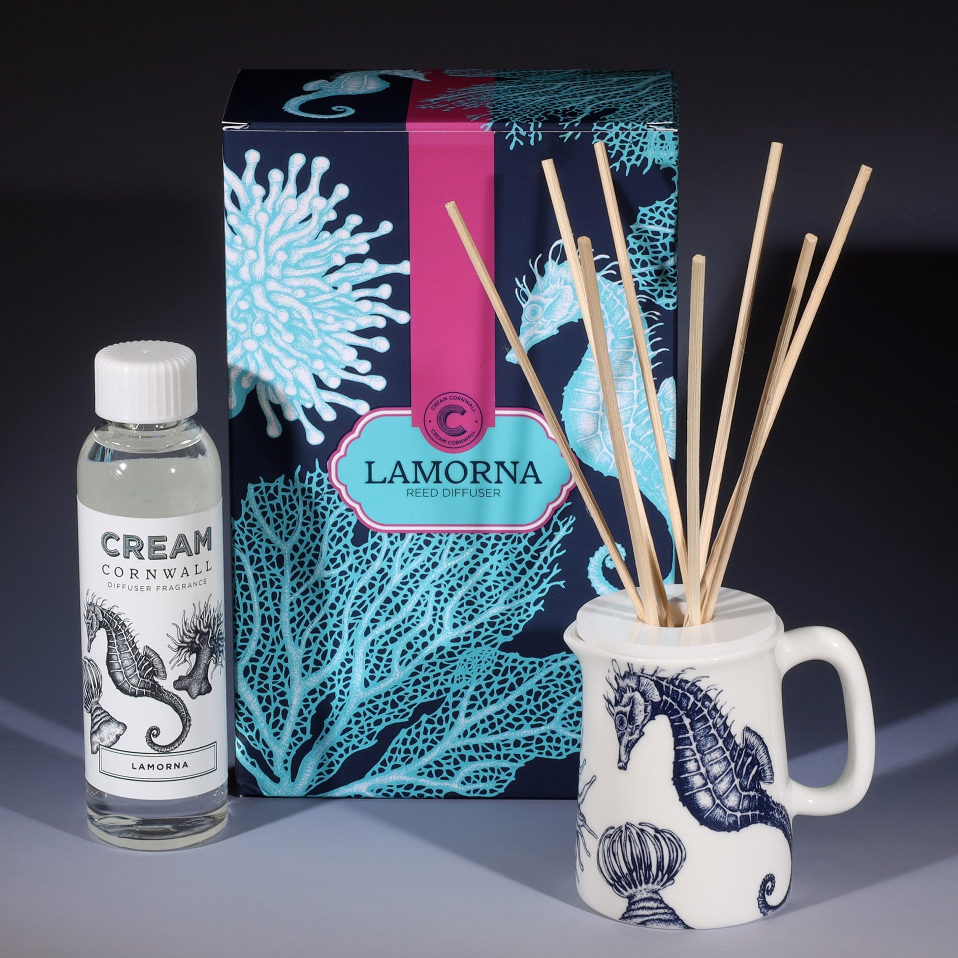 Lamorna room diffuser with natural reeds in front of the product box and a bottle of diffuser liquid.