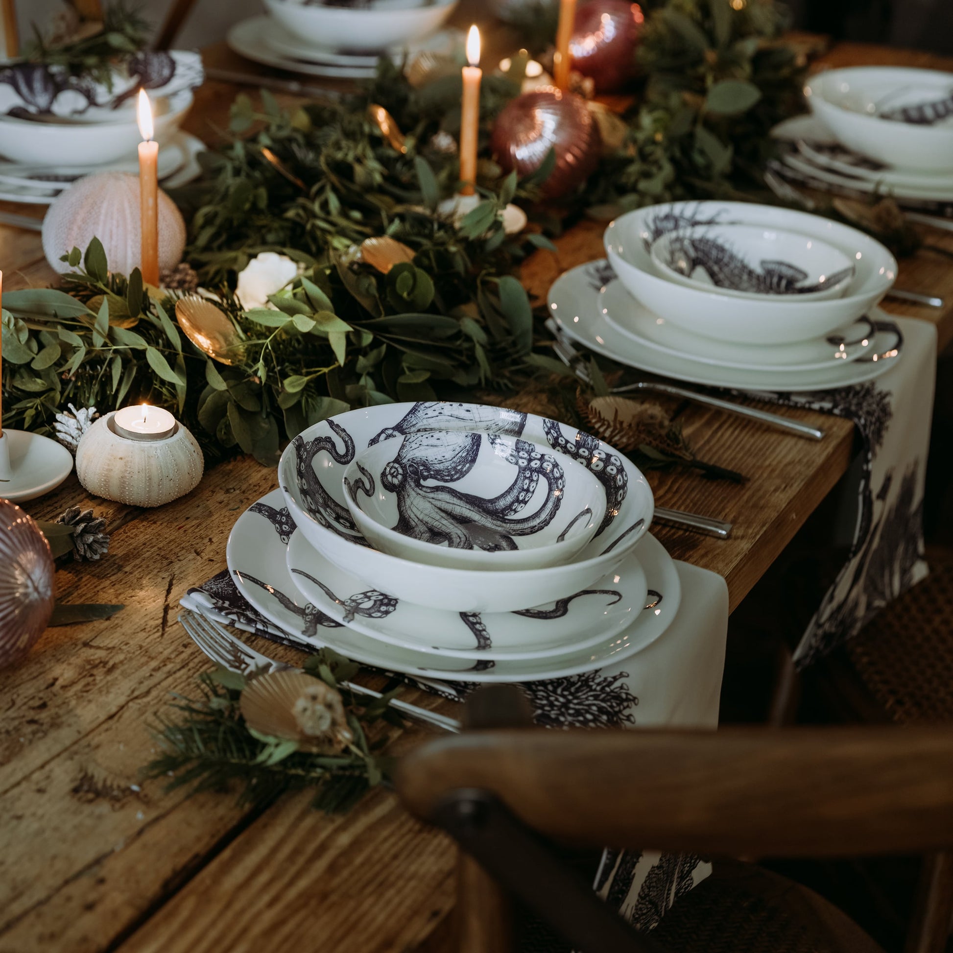 Pasta bowl in Bone China in our Classic range in Navy and white in the Octopus design,placed on a matching dinner plate and has a smaller bowl placed inside.All are on a table setting and the table is decorated with foliage and candle holders.In the background you can see other place settings with matching sets