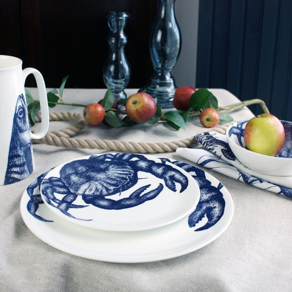 Bone china Crab stack of side and dinner plate on a tablecloth.Also on the table is a bone china jug,a couple of glass candlesticks and other table decorations