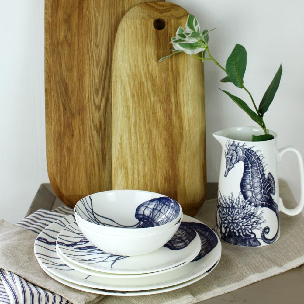 Bone China Octopus Dinner Plate on a stack of jellyfish plates and bowls next to a couple of chopping boards leaning up against the wall behind.Next to them is a matching seahorse jug