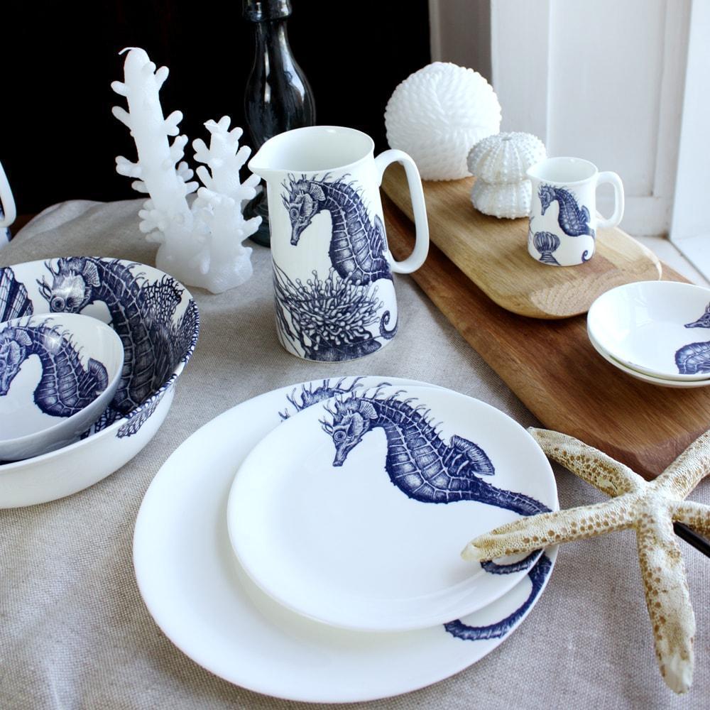 Bone China Seahorse Dinner Plate and side plate on a tablecloth. Behind is a chopping board with some shell decorations on the table and more matching tableware