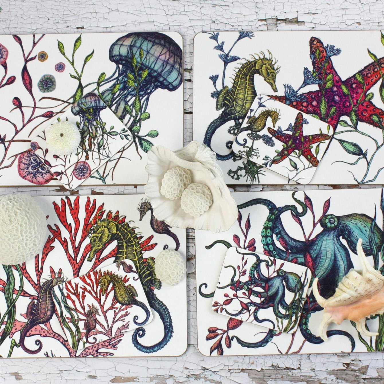 Set of four different coasters in our Reef coloured design with an Octopus,Seahorse,Jellyfish and a Starfish design with matching Placemats.All placed on a table decorated with various shells.