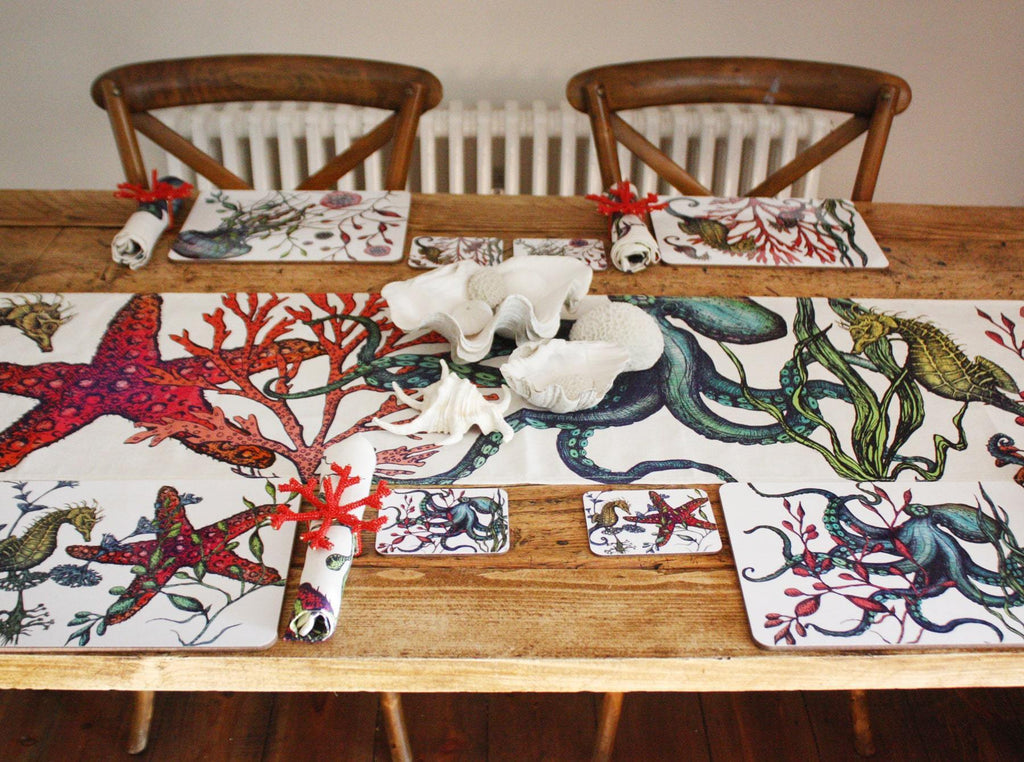 Set of four different coasters in our Reef coloured design with an Octopus,Seahorse,Jellyfish and a Starfish design with matching Placemats.All placed on a table in a place setting,with a matching table runner along the middle of the table.