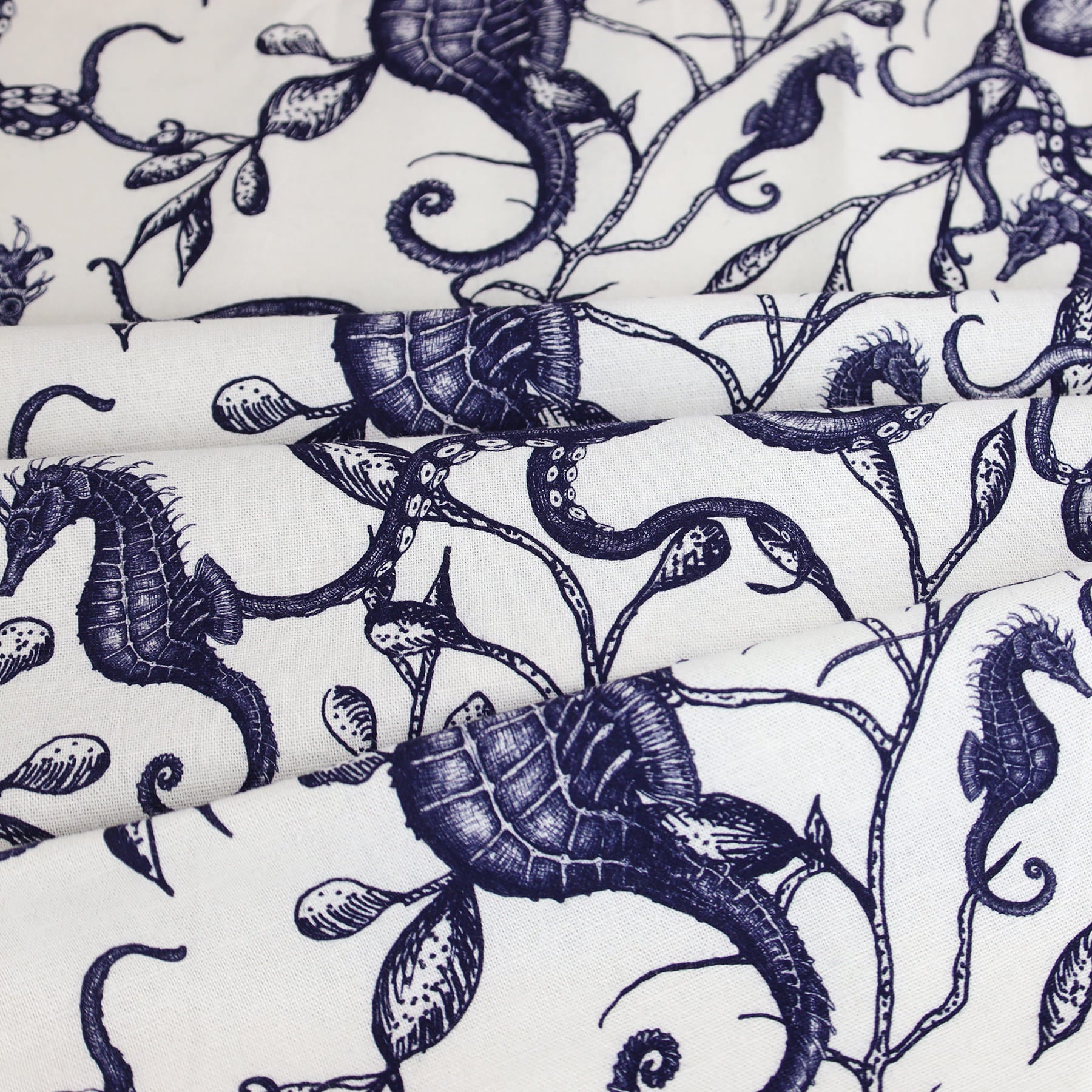Close-up of Cream Cornwall’s fabric featuring a detailed nautical design in navy ink on a white background. The pattern includes hand-drawn illustrations of seahorses, shells, and twisting seaweed tendrils, creating an elegant, coastal-inspired look with a classic marine aesthetic.