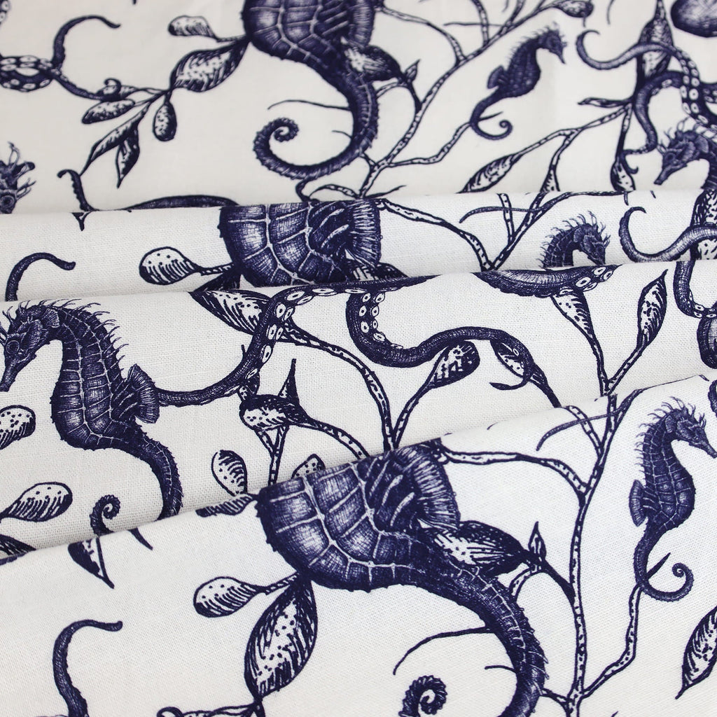 Close-up of Cream Cornwall’s fabric featuring a detailed nautical design in navy ink on a white background. The pattern includes hand-drawn illustrations of seahorses, shells, and twisting seaweed tendrils, creating an elegant, coastal-inspired look with a classic marine aesthetic.